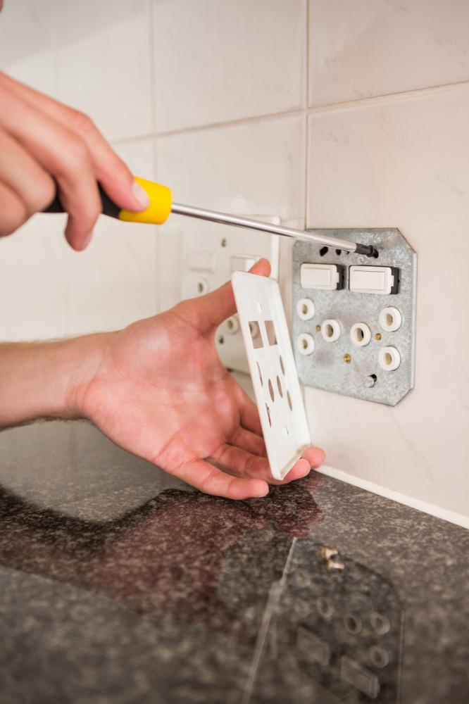 Screwdriver detaching an outlet cover to access wiring